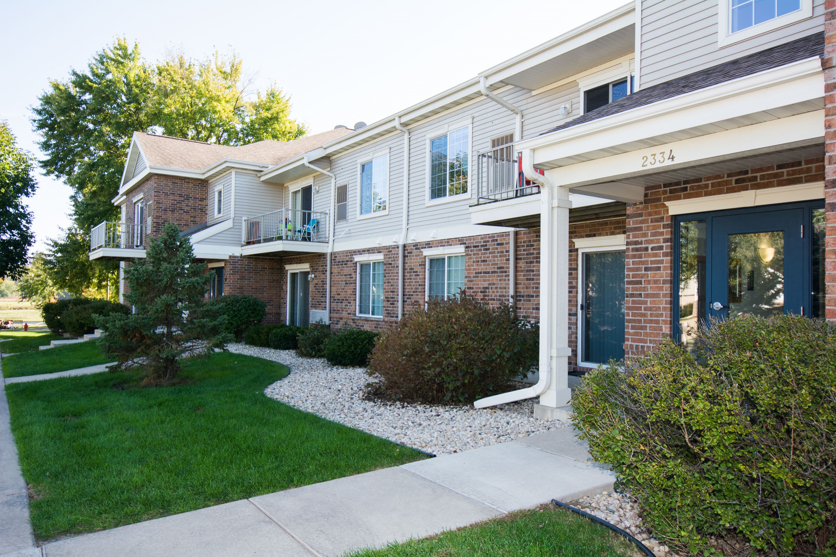 a view of the front of a building with a sidewalk and grass