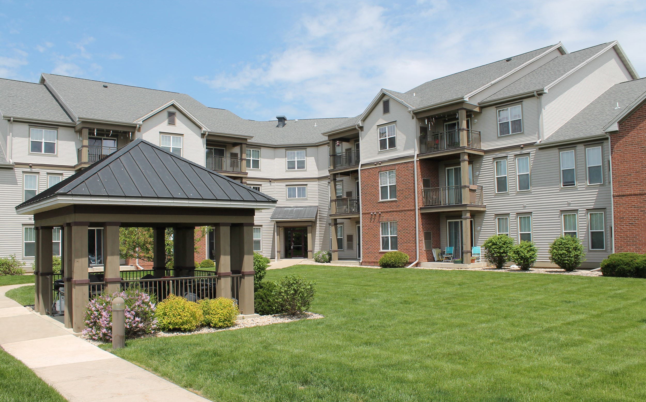 an apartment building with a gazebo and a lawn