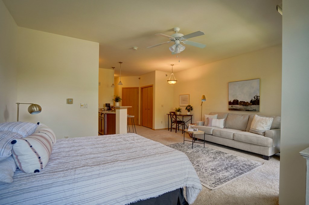 a bedroom with a couch and a bed and a ceiling fan