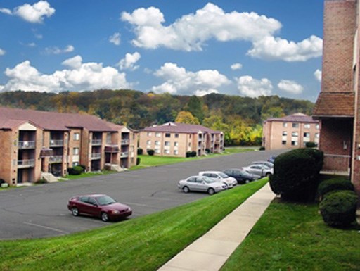 an image of an apartment complex with cars parked in a parking lot