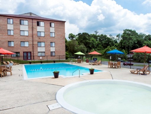 a swimming pool with tables and umbrellas in front of a building