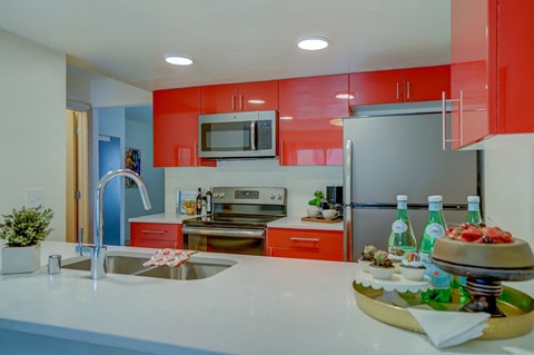 a kitchen with red cabinets and a white counter top and a sink