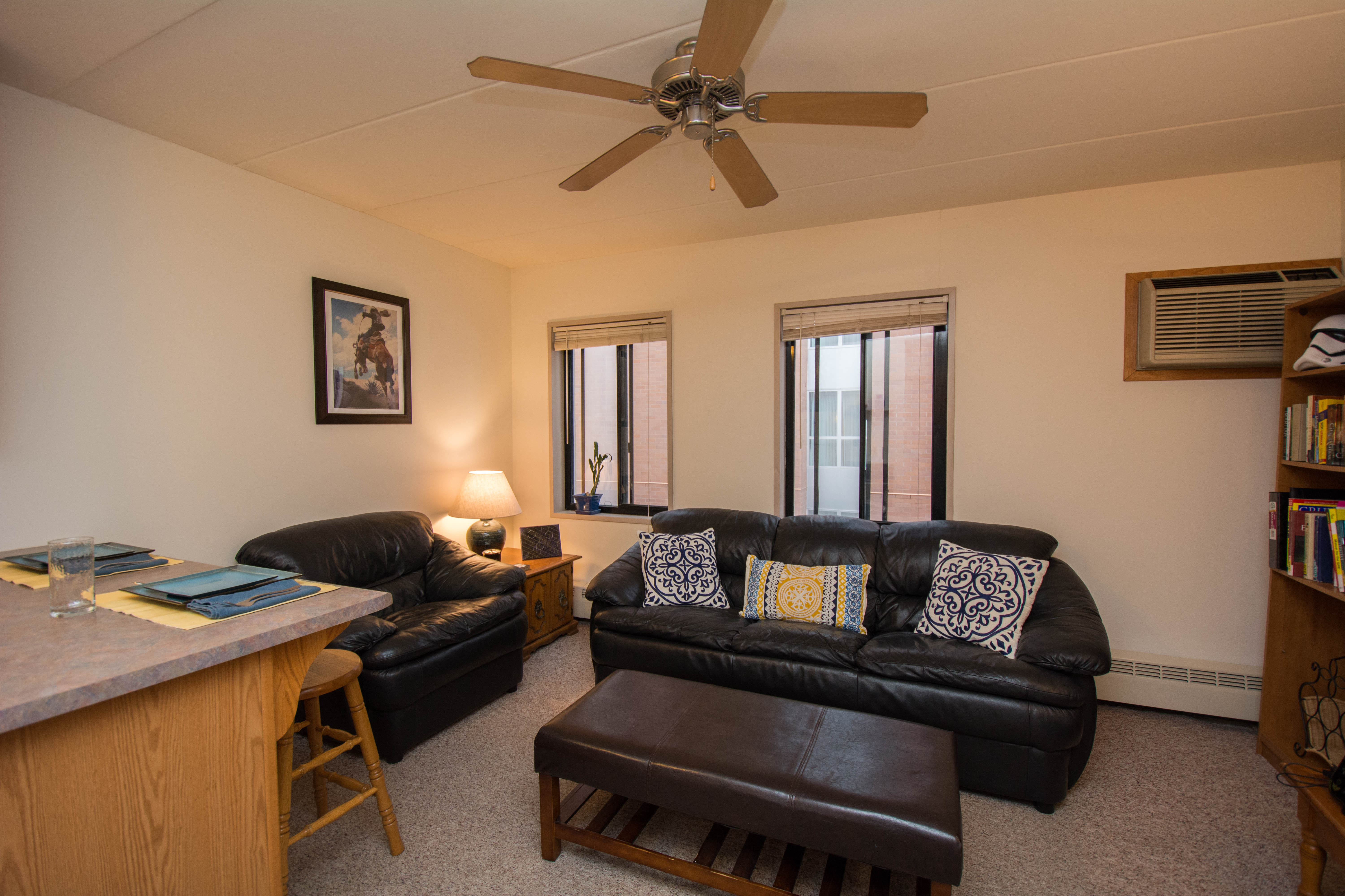 a living room with a couch and a chair and a ceiling fan