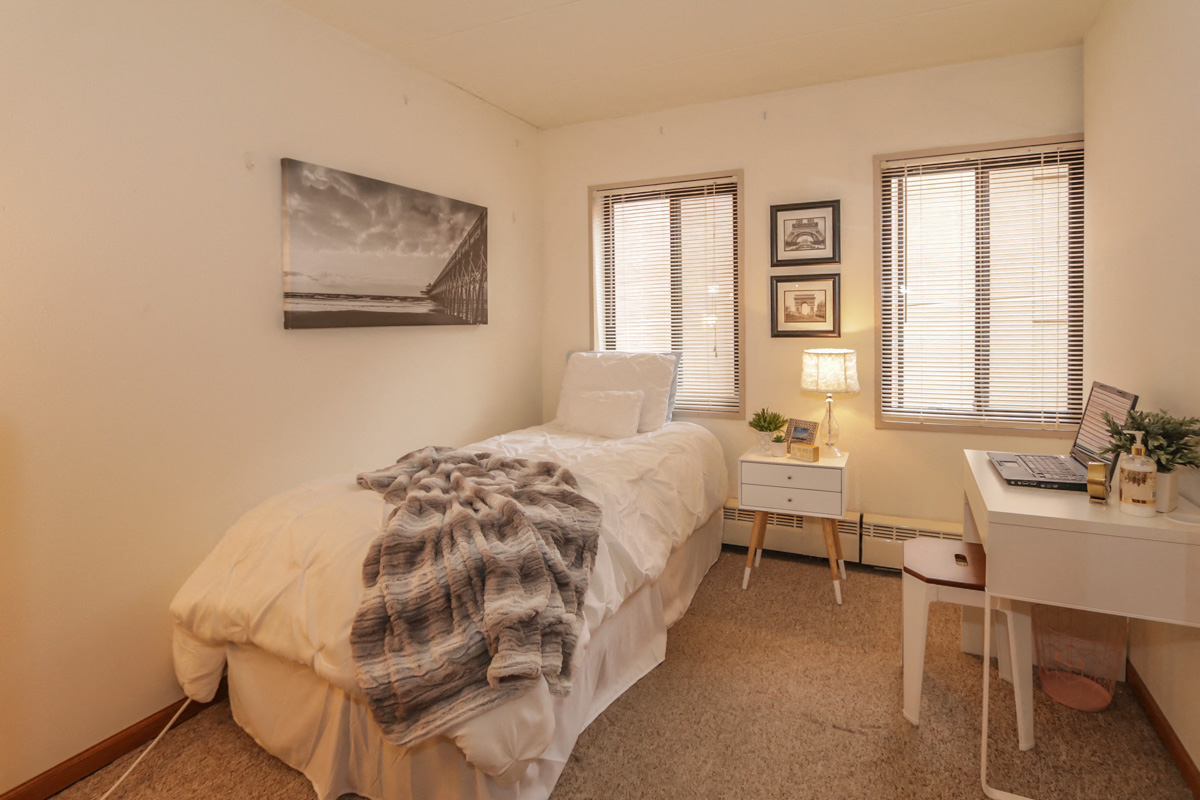 a bedroom with a bed and a desk with a laptop