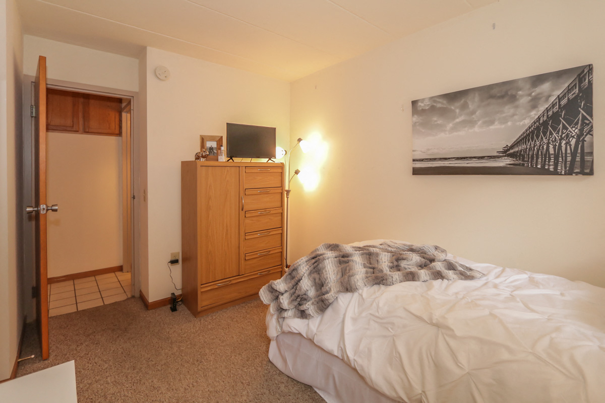 a bedroom with a bed and a dresser with a tv