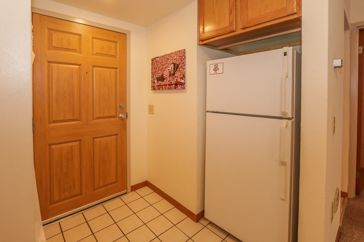 a kitchen with a refrigerator and a wooden door