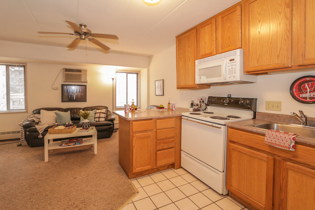 a kitchen and living room with a stove microwave and sink