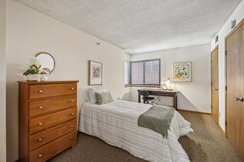A bedroom with a bed, dresser, and desk.