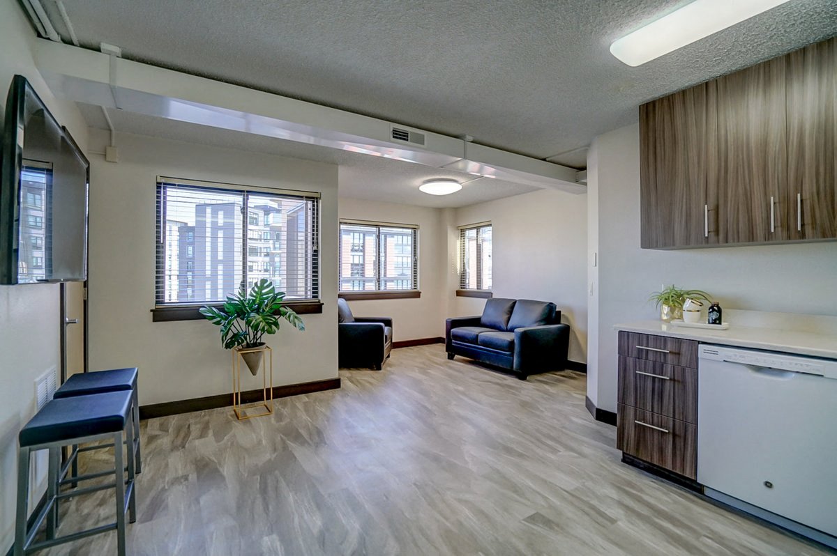 a living room with a kitchen and a bar and a window