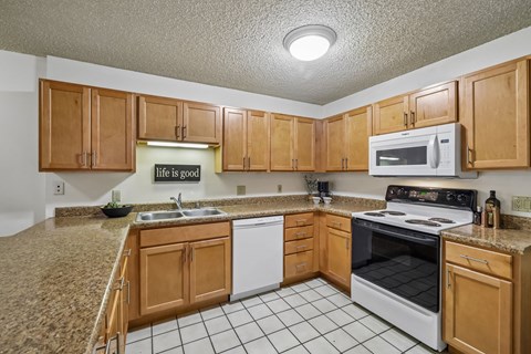 A kitchen with brown cabinets and white appliances.