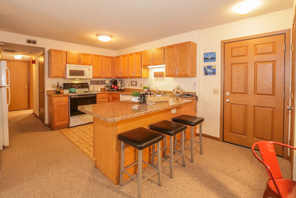 a kitchen with a counter and three stools