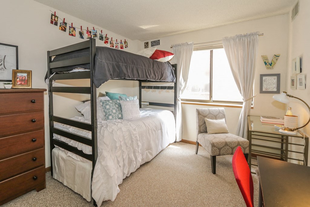 a bunk bed in a room with a desk and a chair