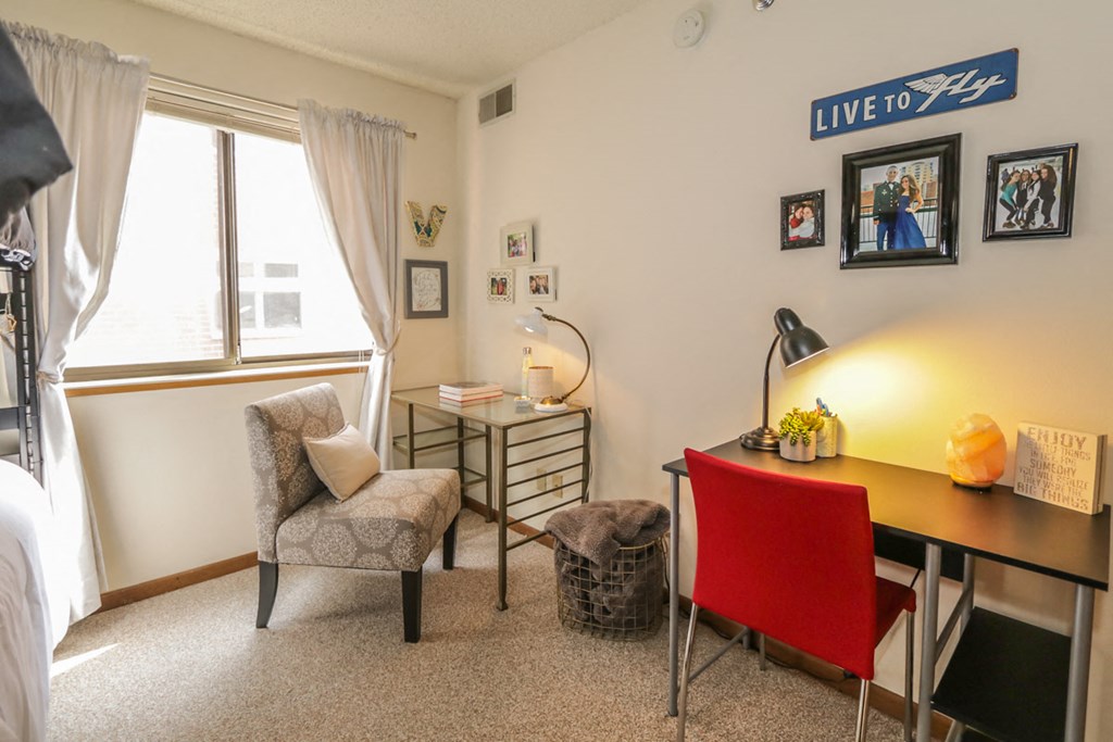 a bedroom with a desk and a chair and a window