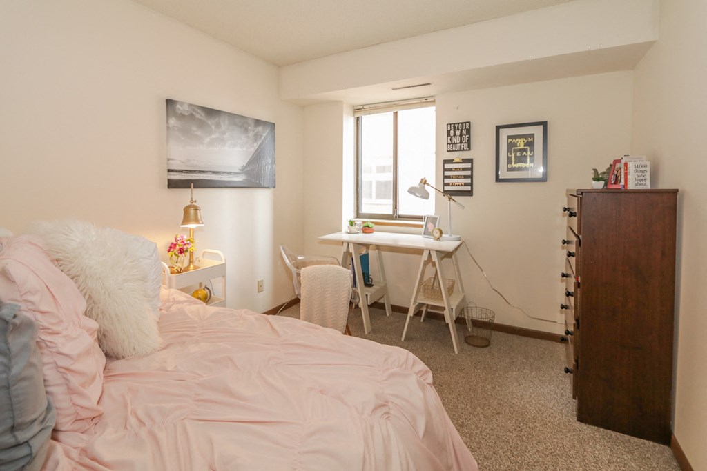 a bedroom with a bed and a desk and a window
