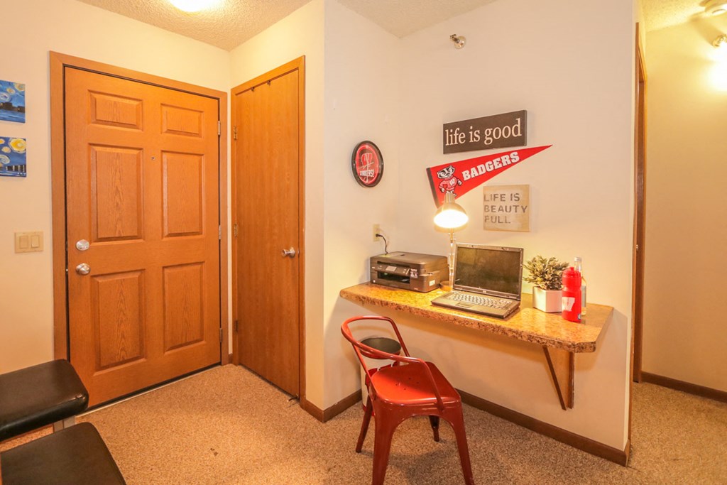 a room with a desk with a computer and a door