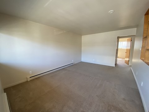 an empty living room with white walls and carpet