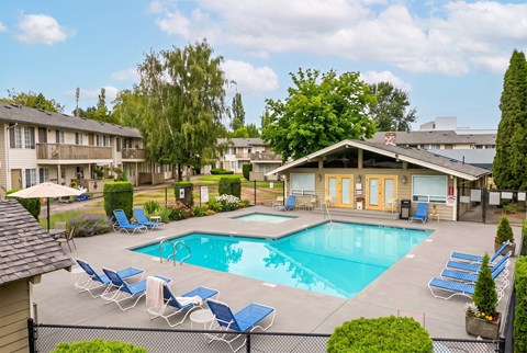 A pool surrounded by lawn chairs and trees.