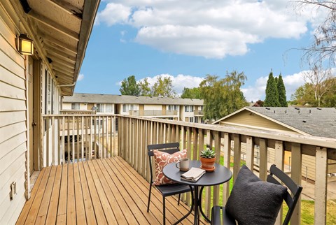 A wooden deck with a table and chairs overlooking apartment buildings.