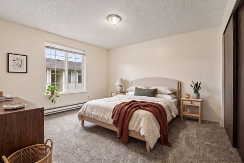 A bedroom with a bed, nightstand, and window.