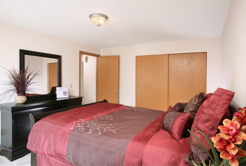 a bedroom with a red bed and a black dresser