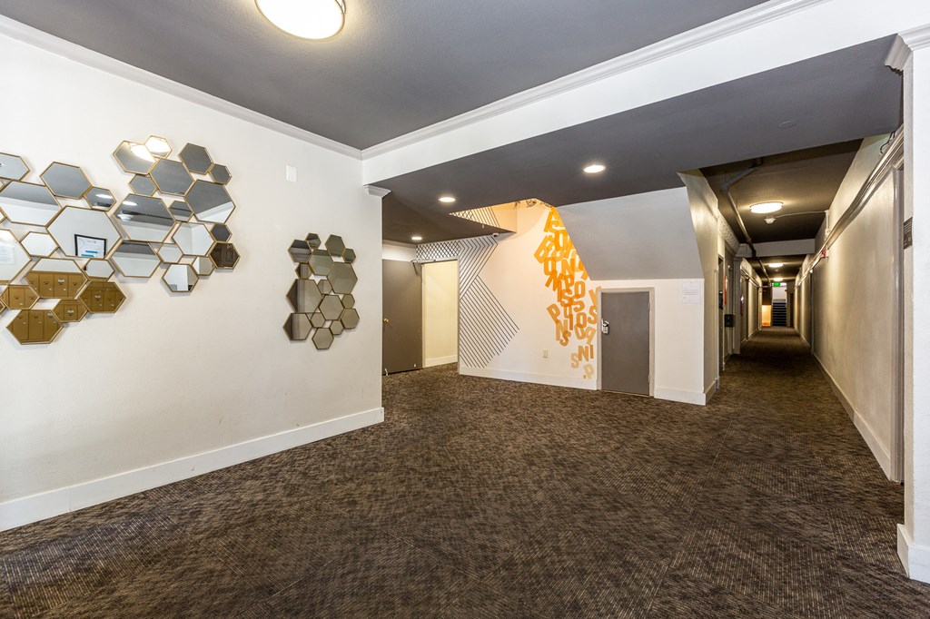 a hallway with a carpeted floor and white walls with geometric shapes on the wall