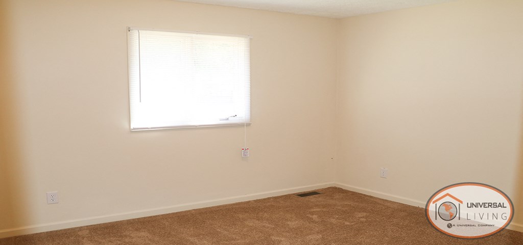 a small room with a window and a carpeted floor