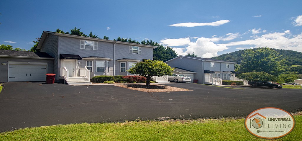 a house with a parking lot and a mountain in the background