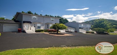 a house with a parking lot and a mountain in the background