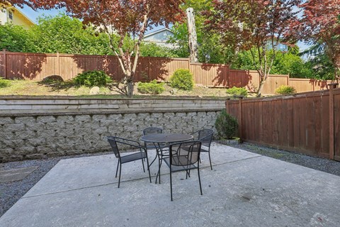 A patio with a table and chairs surrounded by a fence.