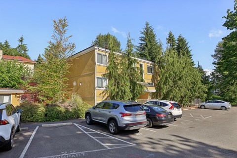 A parking lot with cars and a yellow building in the background.