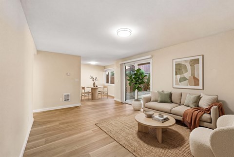 Living room with a sofa, a round coffee table, a sliding glass door to a patio, and a dining area beyond.