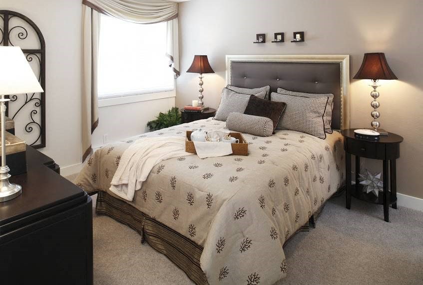 a bedroom with a bed and lamps and a window