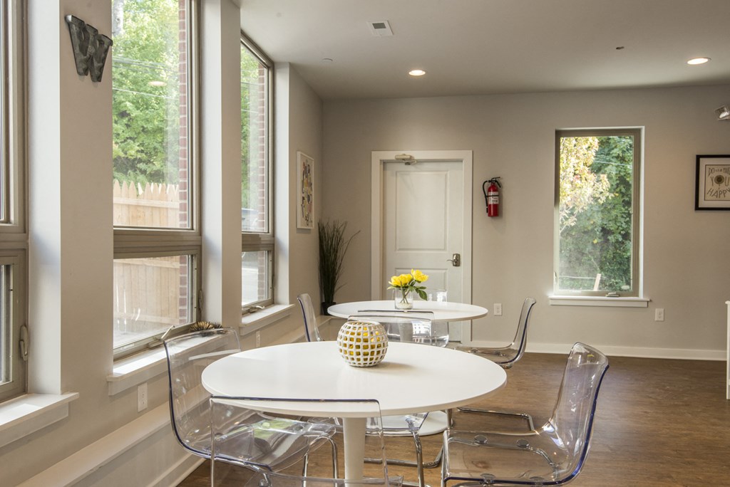 a dining room with white tables and chairs and large windows