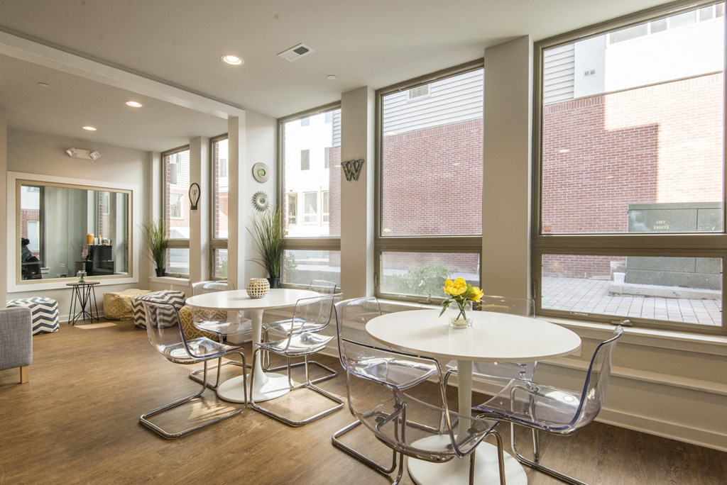 a dining room with white tables and chairs and large windows
