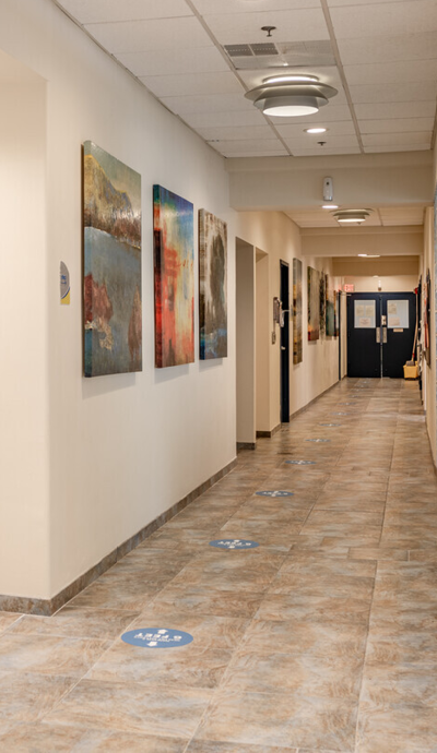 a hallway with paintings on the walls and a tile floor