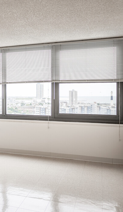 an empty room with three windows overlooking a city