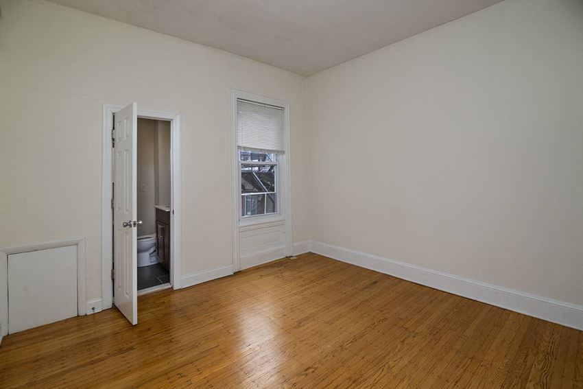 a bedroom with a wood floor and a door to a bathroom
