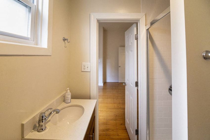 a bathroom with a sink and a mirror and a hallway