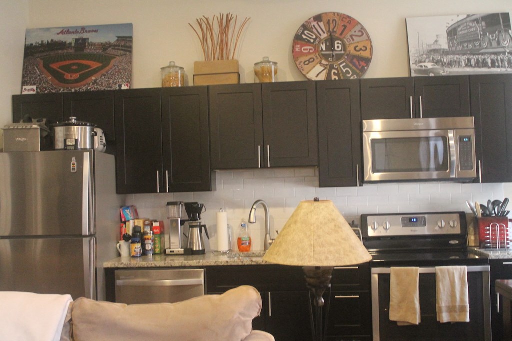 a kitchen with black cabinets and a clock on the wall