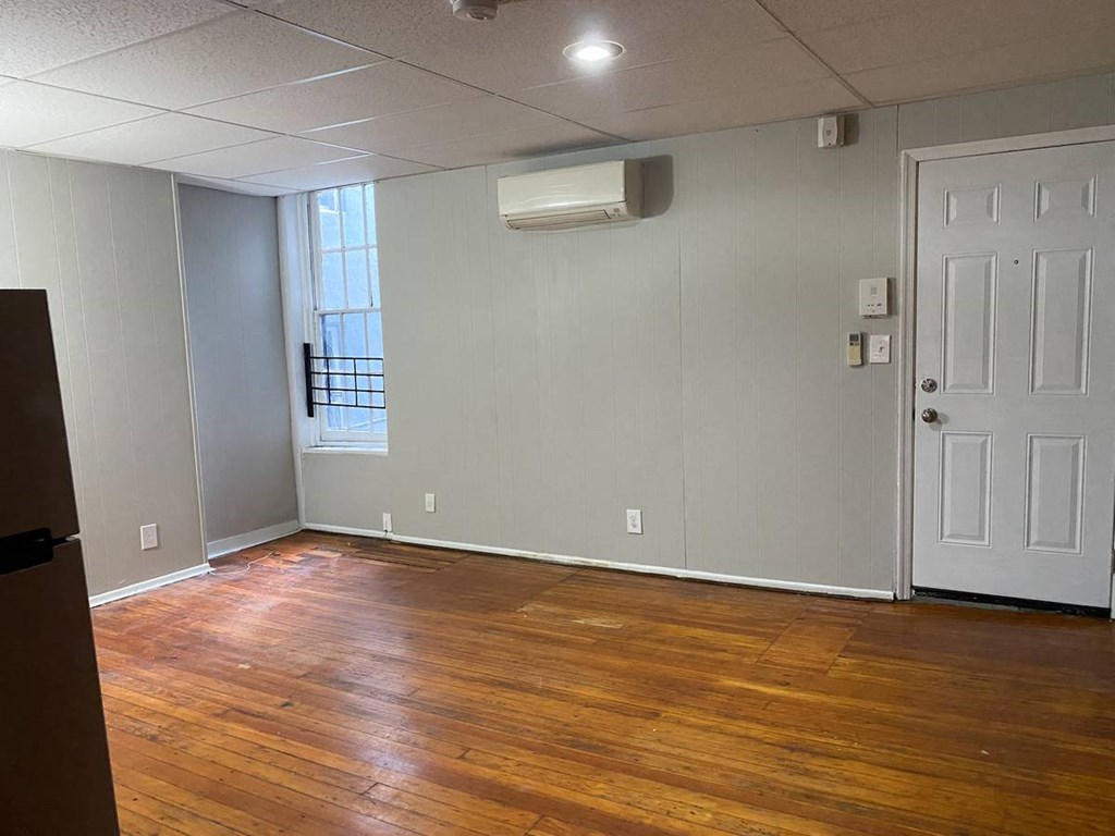 an empty living room with wood floors and a white door
