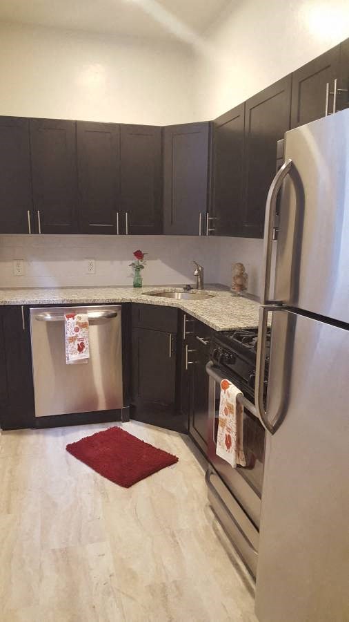 a kitchen with black cabinets and a stainless steel refrigerator