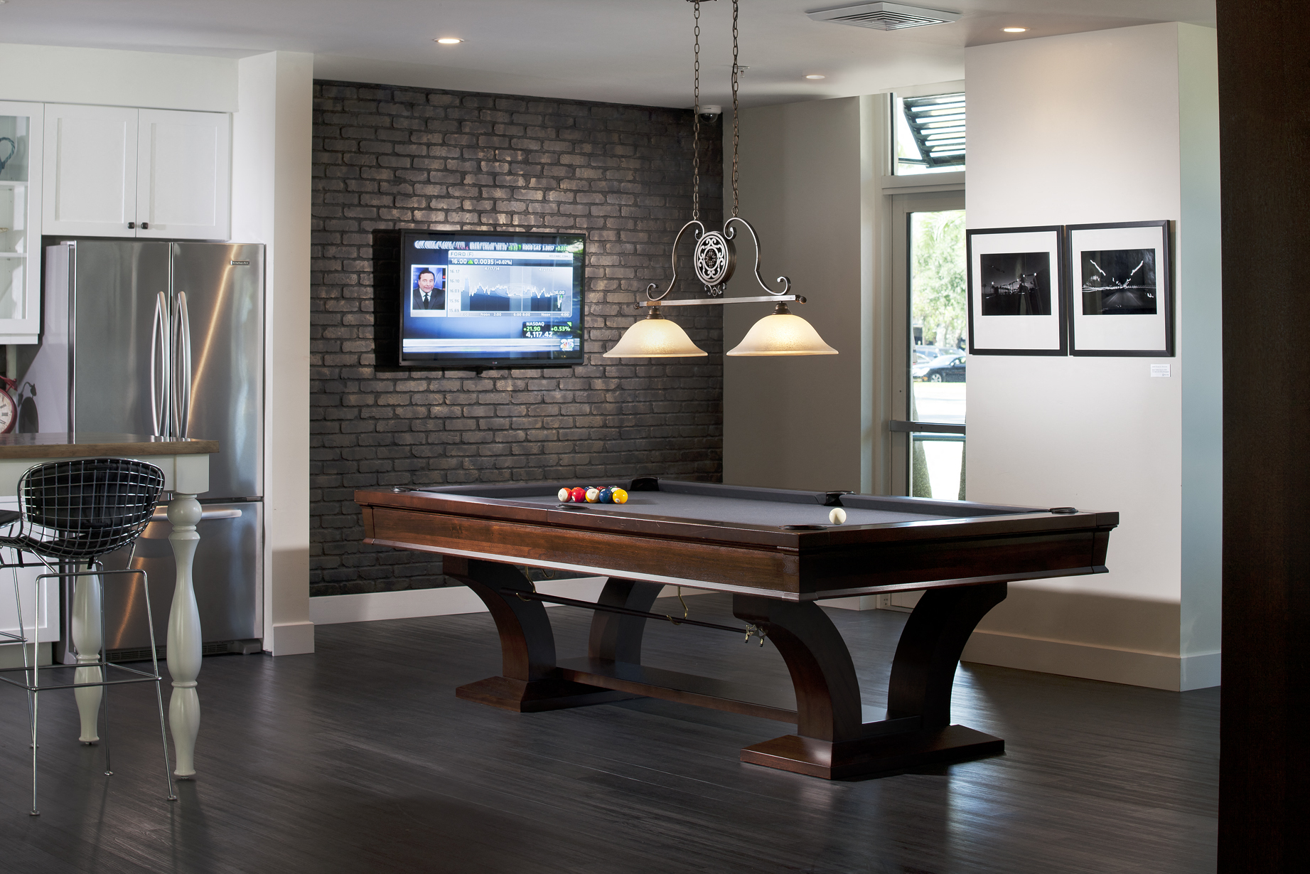 a pool table in a living room with a tv on a brick wall