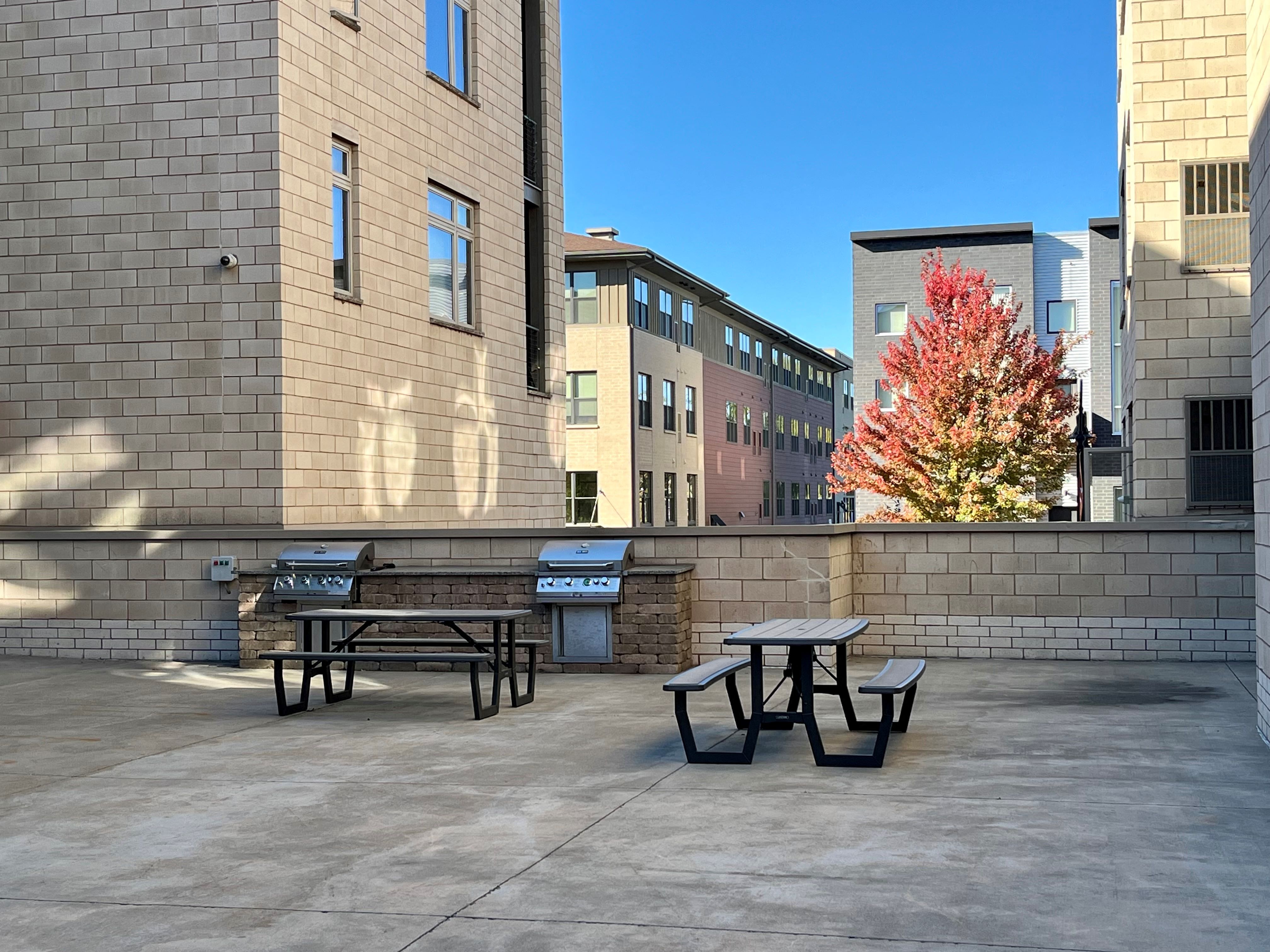a patio with picnic tables and benches on the side of a building