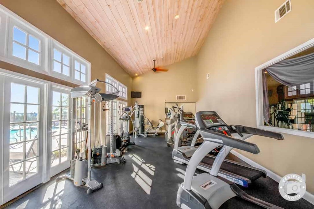 a gym with cardio machines and a window overlooking a swimming pool