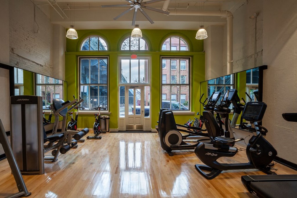 a gym with treadmills and weights in a room with windows