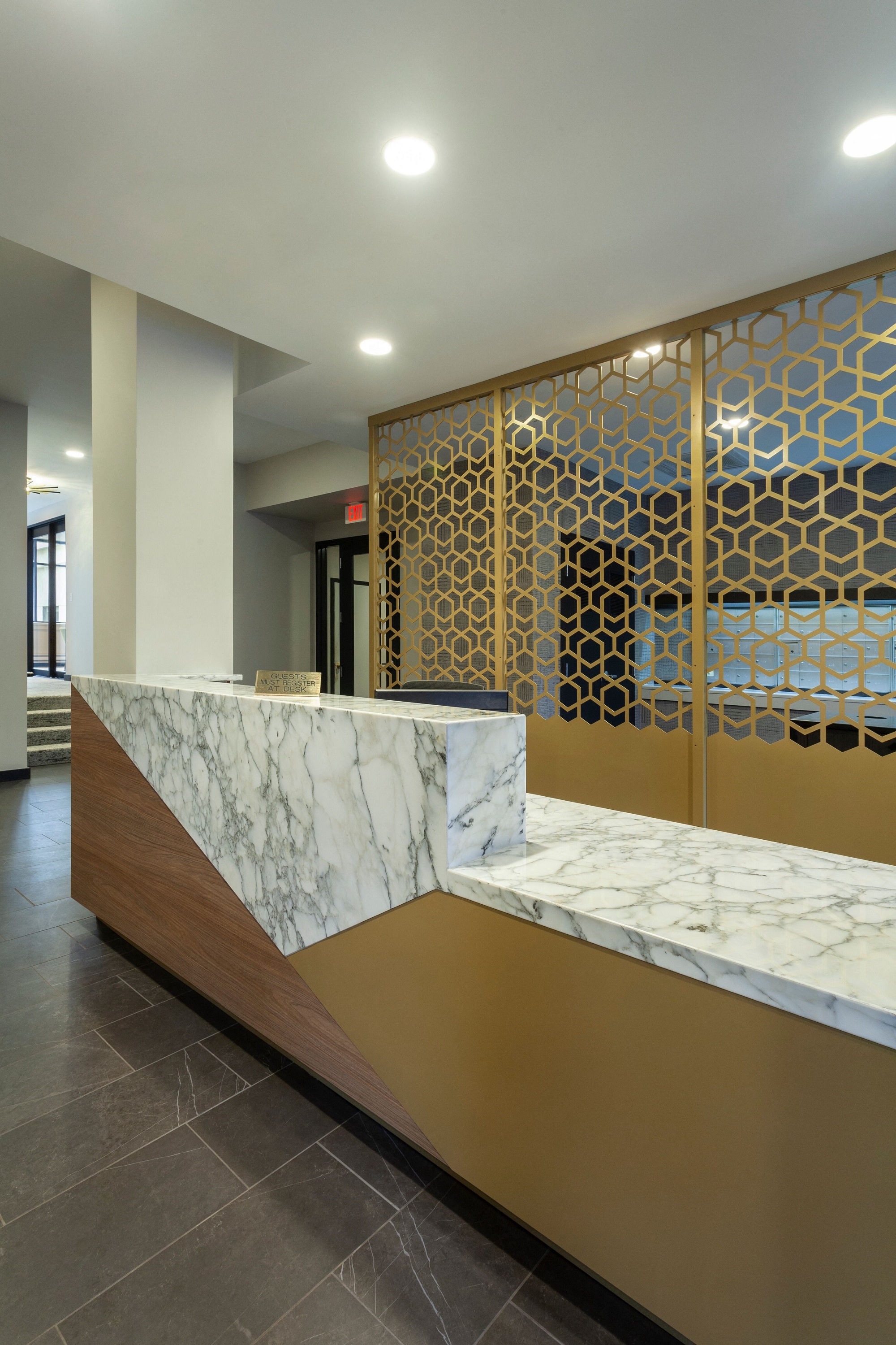 a reception desk in a hotel lobby with a marble counter top and gold wallpaper