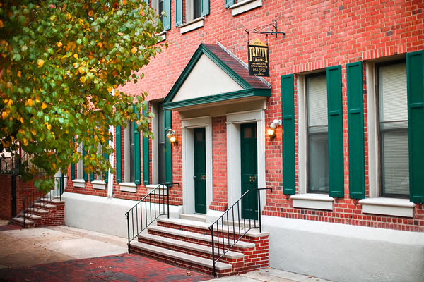 a red brick building with green doors and stairs