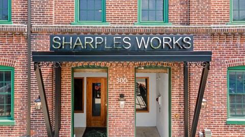 A red brick building with a black awning that says Sharple's Works.