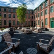 a courtyard with chairs and tables in front of a brick building