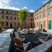 a courtyard with chairs and tables in front of a brick building